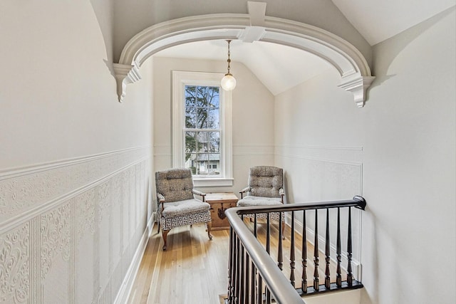 interior space featuring lofted ceiling, arched walkways, wainscoting, and wood finished floors