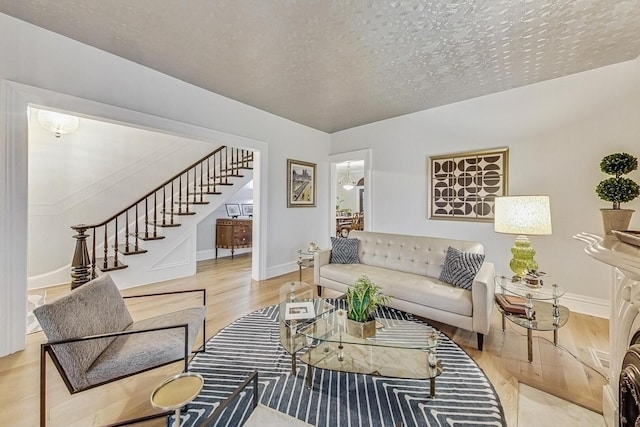 living area with a textured ceiling, stairway, wood finished floors, and baseboards