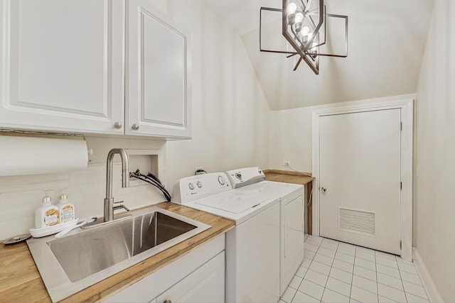 laundry room with washing machine and clothes dryer, light tile patterned floors, cabinet space, visible vents, and a sink