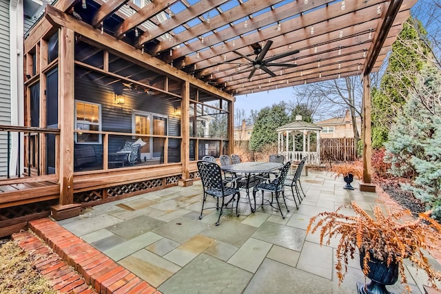 view of patio / terrace with ceiling fan, fence, a gazebo, a pergola, and outdoor dining space