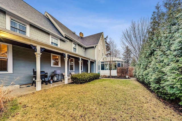 view of side of property featuring a yard, a porch, and a chimney