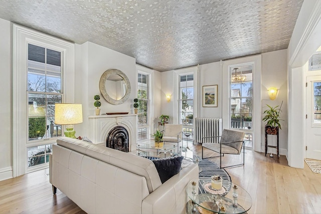 living room with a fireplace, hardwood / wood-style floors, radiator heating unit, and a textured ceiling