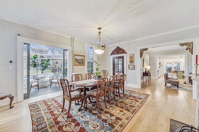 dining area with light wood-style floors, ornamental molding, and baseboards