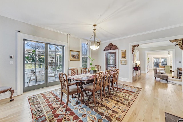 dining area featuring light wood-style flooring, ornamental molding, baseboards, and french doors