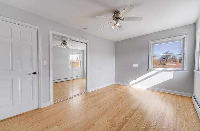 spare room featuring light wood-type flooring, a baseboard heating unit, baseboards, and a ceiling fan