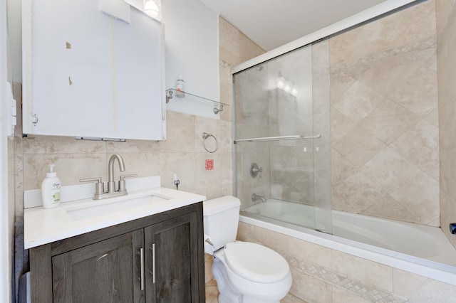 bathroom with vanity, tile walls, toilet, and tiled shower / bath combo