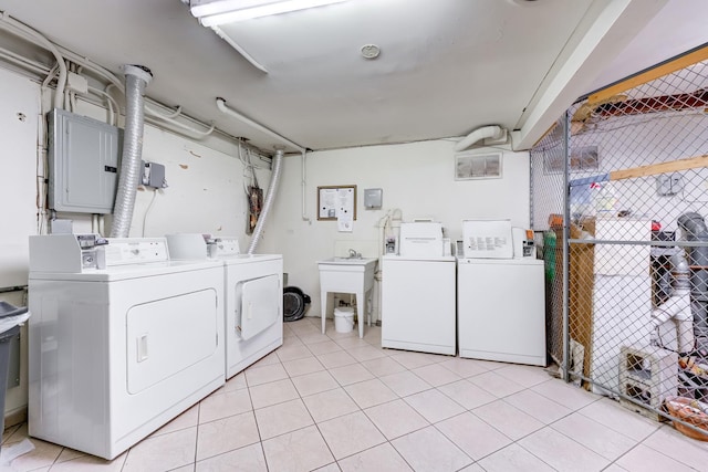 common laundry area featuring electric panel, light tile patterned floors, a sink, and washer and clothes dryer