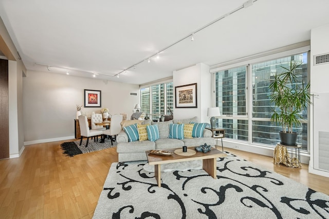 living room featuring baseboards, wood finished floors, and rail lighting