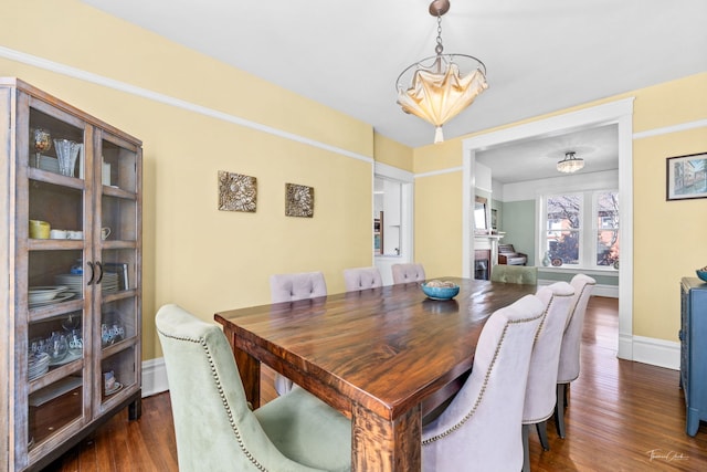 dining area featuring dark wood-style floors, baseboards, and a chandelier