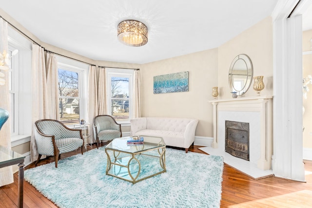 living room with a fireplace with flush hearth, baseboards, and wood finished floors