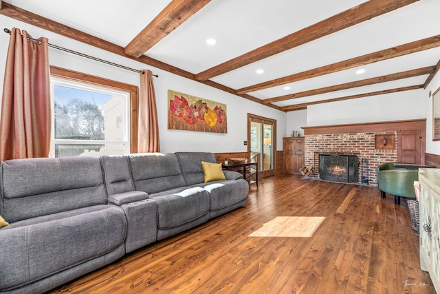 living area with beam ceiling, recessed lighting, a brick fireplace, and hardwood / wood-style floors