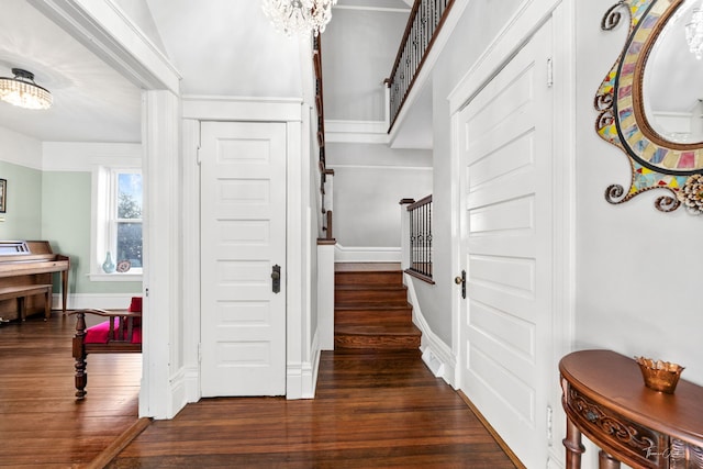 foyer entrance featuring an inviting chandelier, stairs, baseboards, and wood finished floors