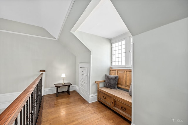 hallway with light wood-style floors, lofted ceiling, and an upstairs landing