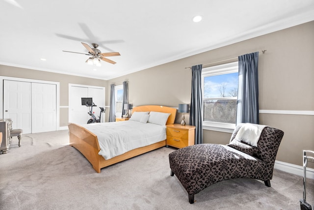 carpeted bedroom with multiple windows, ceiling fan, baseboards, and two closets