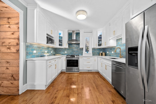 kitchen featuring a sink, light countertops, appliances with stainless steel finishes, wall chimney range hood, and tasteful backsplash