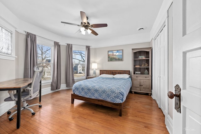 bedroom with light wood-type flooring, ceiling fan, and baseboards