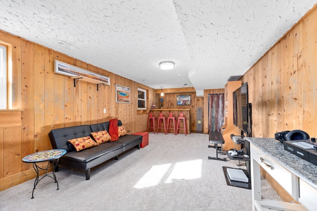 carpeted living room with wood walls, a textured ceiling, and a bar