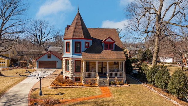 victorian home with covered porch, a garage, a shingled roof, stone siding, and a front yard