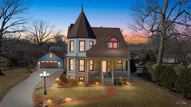 victorian house featuring an outbuilding, a detached garage, a porch, a lawn, and stone siding