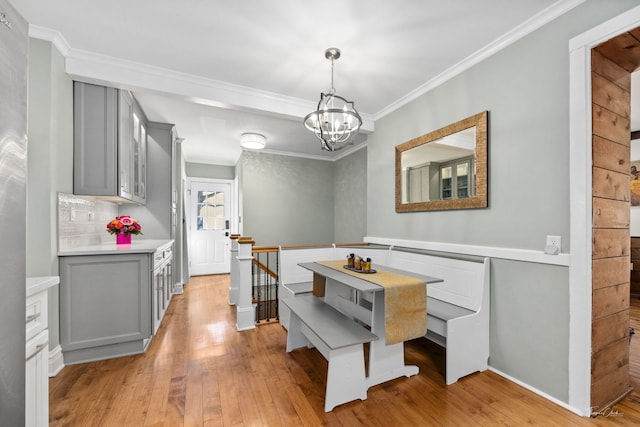 dining area with light wood-style floors, a chandelier, and crown molding