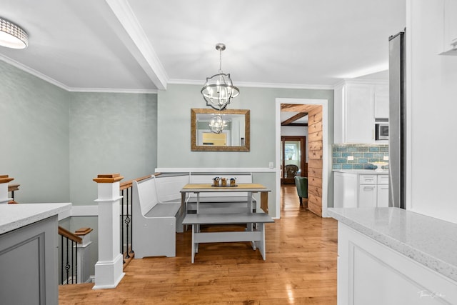 dining space featuring light wood-type flooring, crown molding, and an inviting chandelier