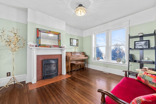 living room featuring a fireplace with flush hearth, visible vents, baseboards, wood-type flooring, and an inviting chandelier