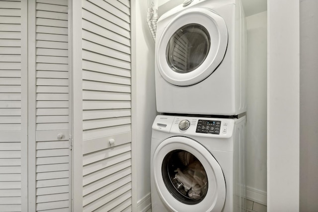 washroom with laundry area, baseboards, and stacked washer / dryer