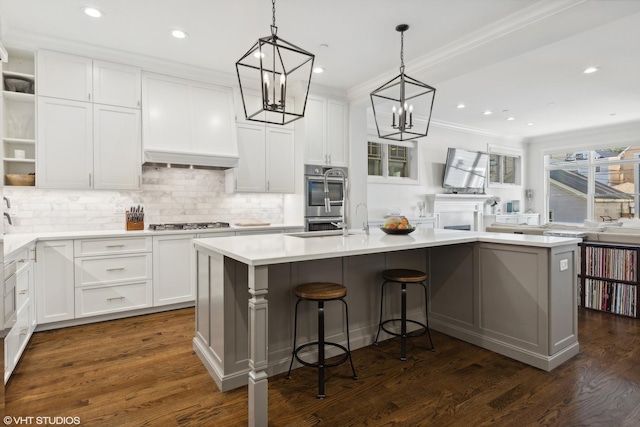 kitchen with crown molding, open shelves, stainless steel appliances, white cabinets, and an island with sink