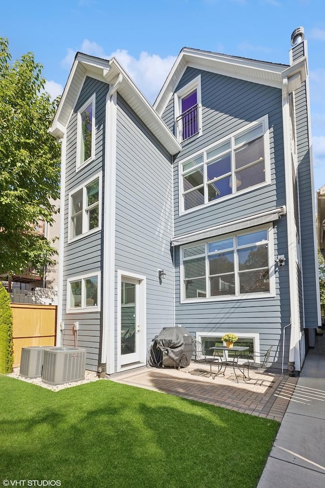 back of property featuring a yard, a chimney, cooling unit, and a patio