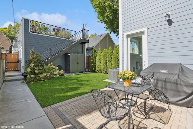 view of patio featuring an outbuilding, a grill, stairs, fence, and a shed