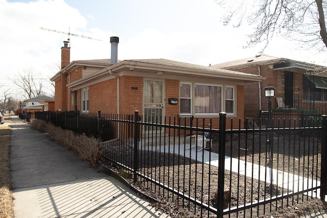 view of front of house featuring a fenced front yard, a chimney, and brick siding