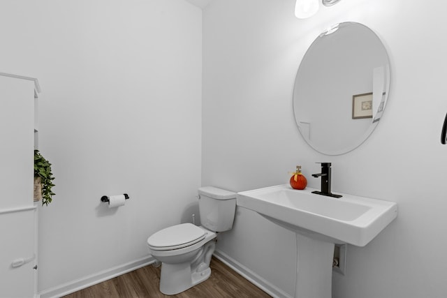 half bathroom with toilet, baseboards, and wood finished floors