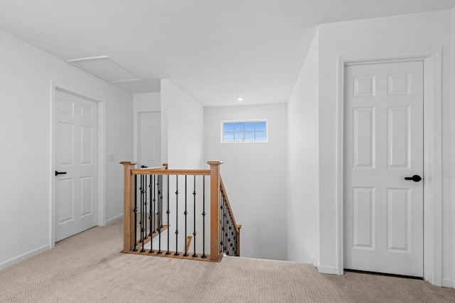 corridor featuring baseboards, carpet floors, an upstairs landing, and attic access