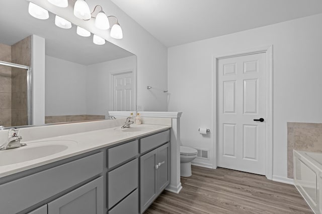 full bathroom featuring double vanity, visible vents, toilet, a stall shower, and a sink