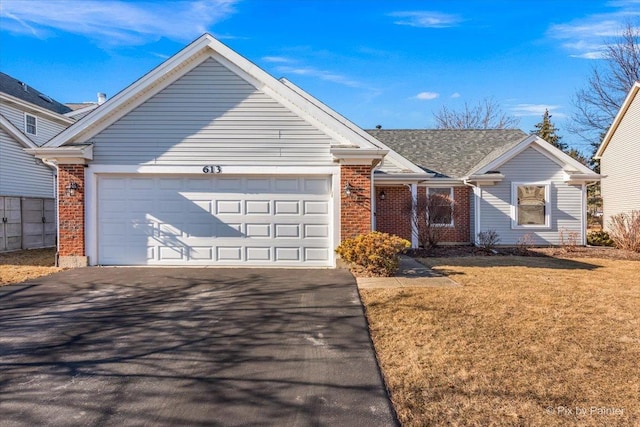 single story home featuring driveway, brick siding, an attached garage, and a front yard