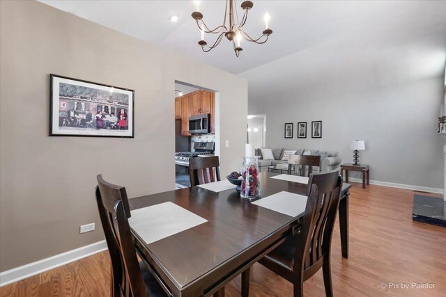 dining area featuring light wood-style flooring, baseboards, and an inviting chandelier