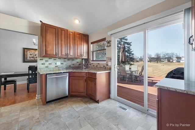 kitchen with brown cabinets, visible vents, a sink, and stainless steel dishwasher