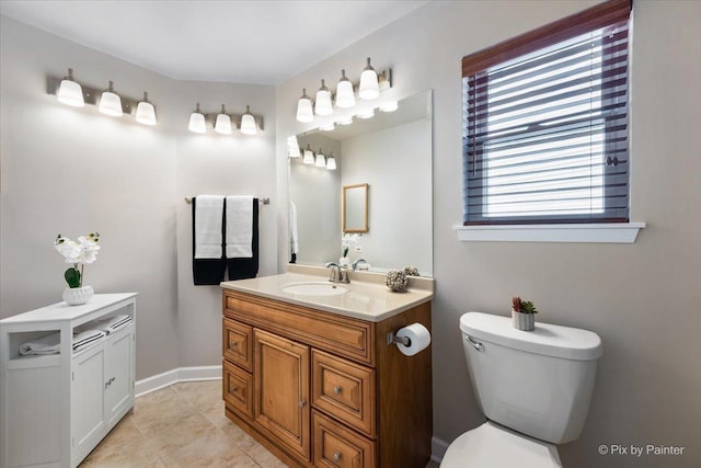 bathroom with tile patterned flooring, baseboards, vanity, and toilet