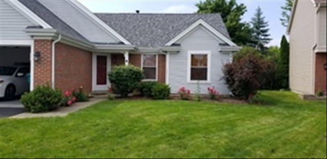 view of front of home featuring a garage, brick siding, driveway, and a front yard