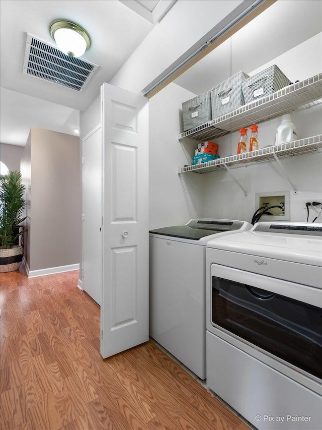 laundry room with light wood-style floors, laundry area, visible vents, and separate washer and dryer