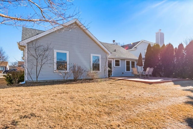 back of house with a patio and a lawn