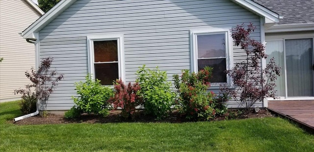 view of home's exterior with a yard and roof with shingles