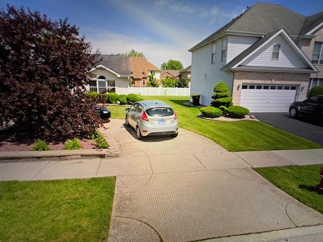 view of property exterior featuring a garage, a yard, driveway, and fence