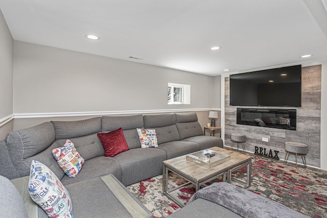 living room with a large fireplace, visible vents, and recessed lighting