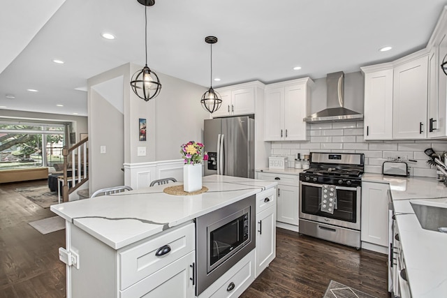 kitchen with stainless steel appliances, dark wood-style flooring, white cabinets, and wall chimney range hood