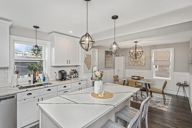 kitchen featuring dark wood-style floors, tasteful backsplash, stainless steel dishwasher, white cabinetry, and a kitchen island