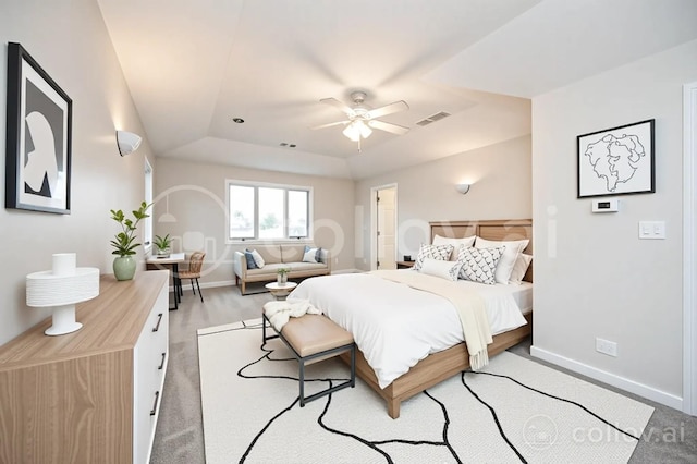 bedroom with visible vents, baseboards, a tray ceiling, and ceiling fan