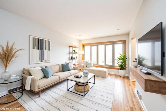 living area featuring visible vents, light wood-type flooring, and baseboards