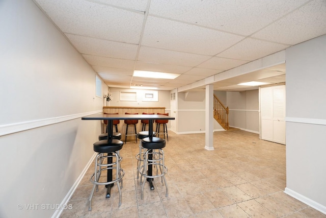 interior space featuring bar, baseboards, stairway, and a paneled ceiling