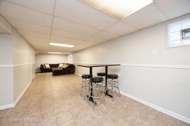 interior space with a paneled ceiling and baseboards